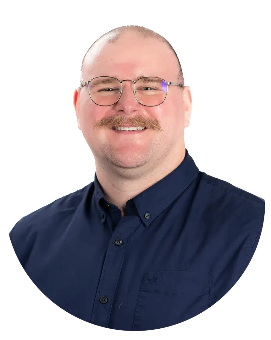 A person wearing glasses and a dark blue button-up shirt, smiling, with a white background.