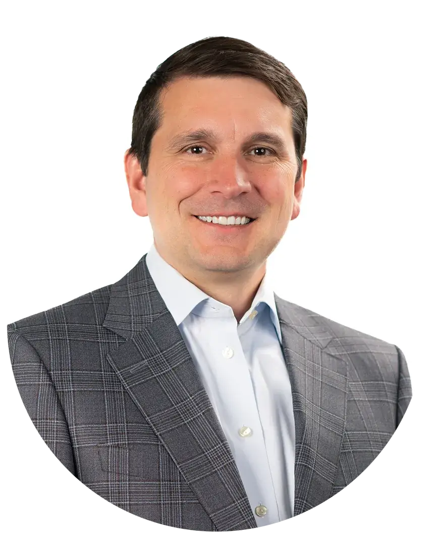 Man with short dark hair wearing a gray plaid suit jacket and white shirt, smiling, posed against a white background.