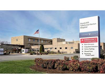 Vanderbilt Tullahoma-Harton Hospital with a U.S. flag, main entrance, and a sign listing emergency and other facility services in front.