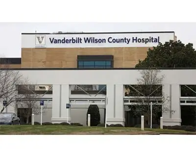 Exterior view of Vanderbilt Wilson County Hospital building with its name visible on the sign and some trees and parking spaces in front.